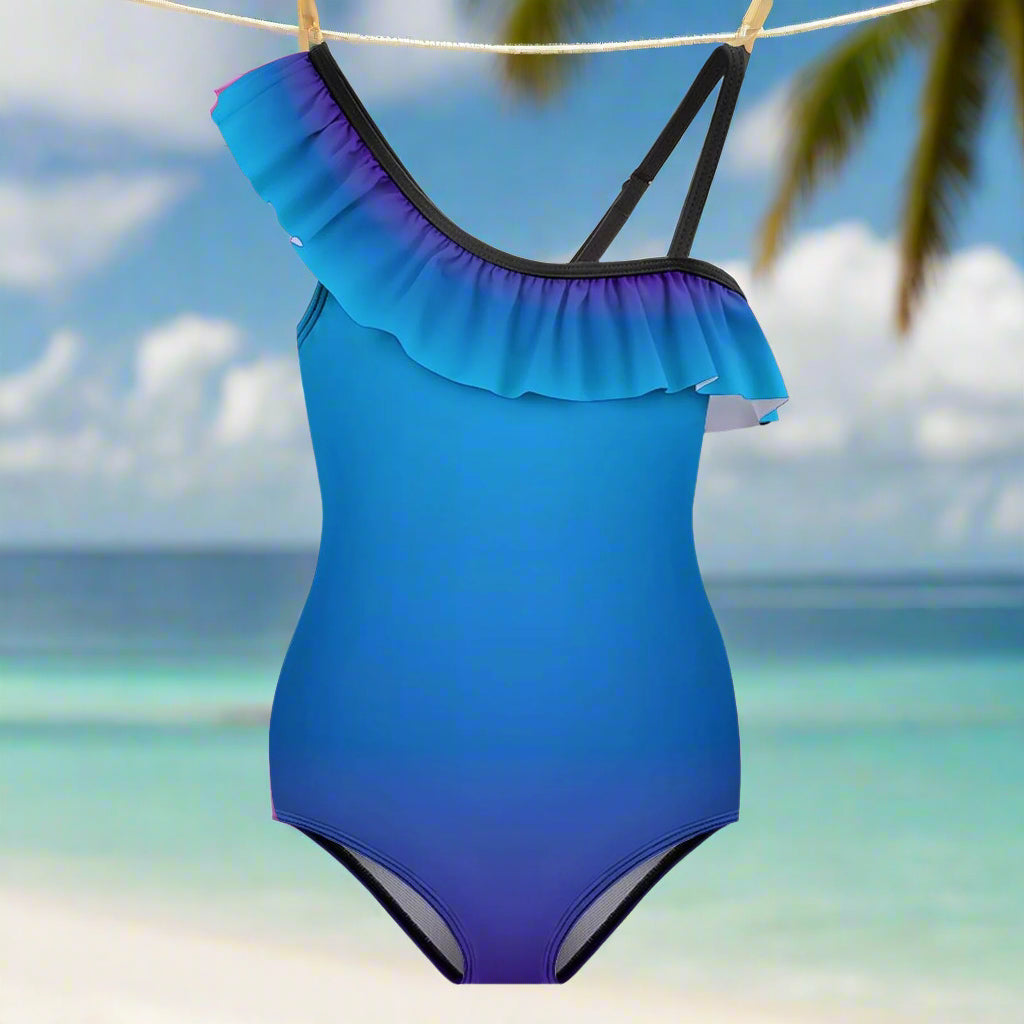 Blue one-piece swimsuit with ruffled shoulder design hanging on a line in a beach island paradise