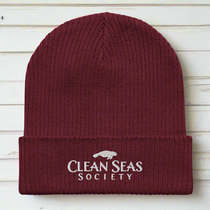 Organic Burgundy Beanie with Clean Seas Society logo over nautical wood