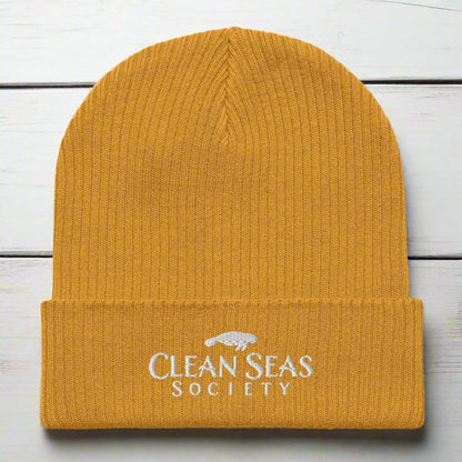 Mustard Yellow Organic Ribbed Beanie with Clean Seas Society logo on a nautical wood background