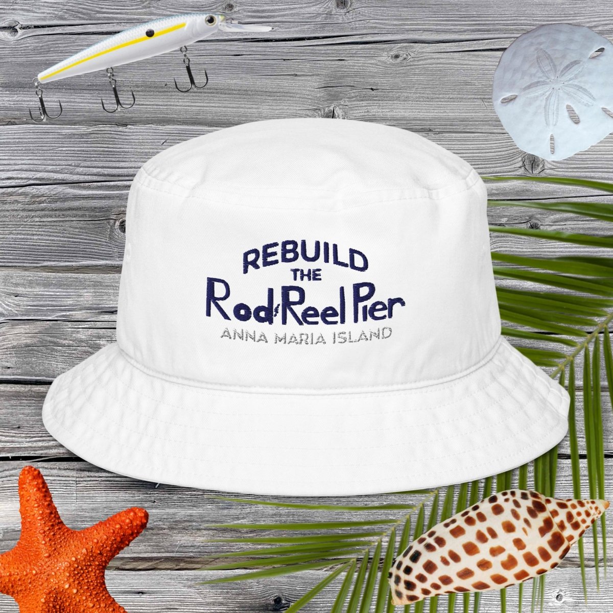 White bucket hat with text on a wooden background with beach elements.