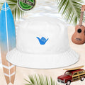 White Shaka bucket hat with blue shaka embroidery, on a beach background with surfboard, a vintage model beach woody car, and a ukulele