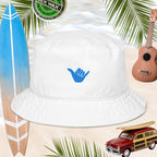 White bucket hat with blue shaka embroidery, on a beach background with surfboard, a vintage model beach woody car, and a ukulele
