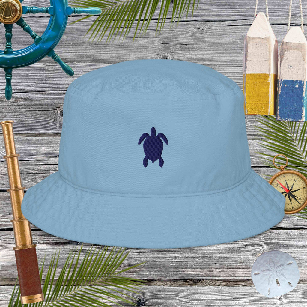 Blue bucket hat with a turtle emblem on a wooden background with nautical items.