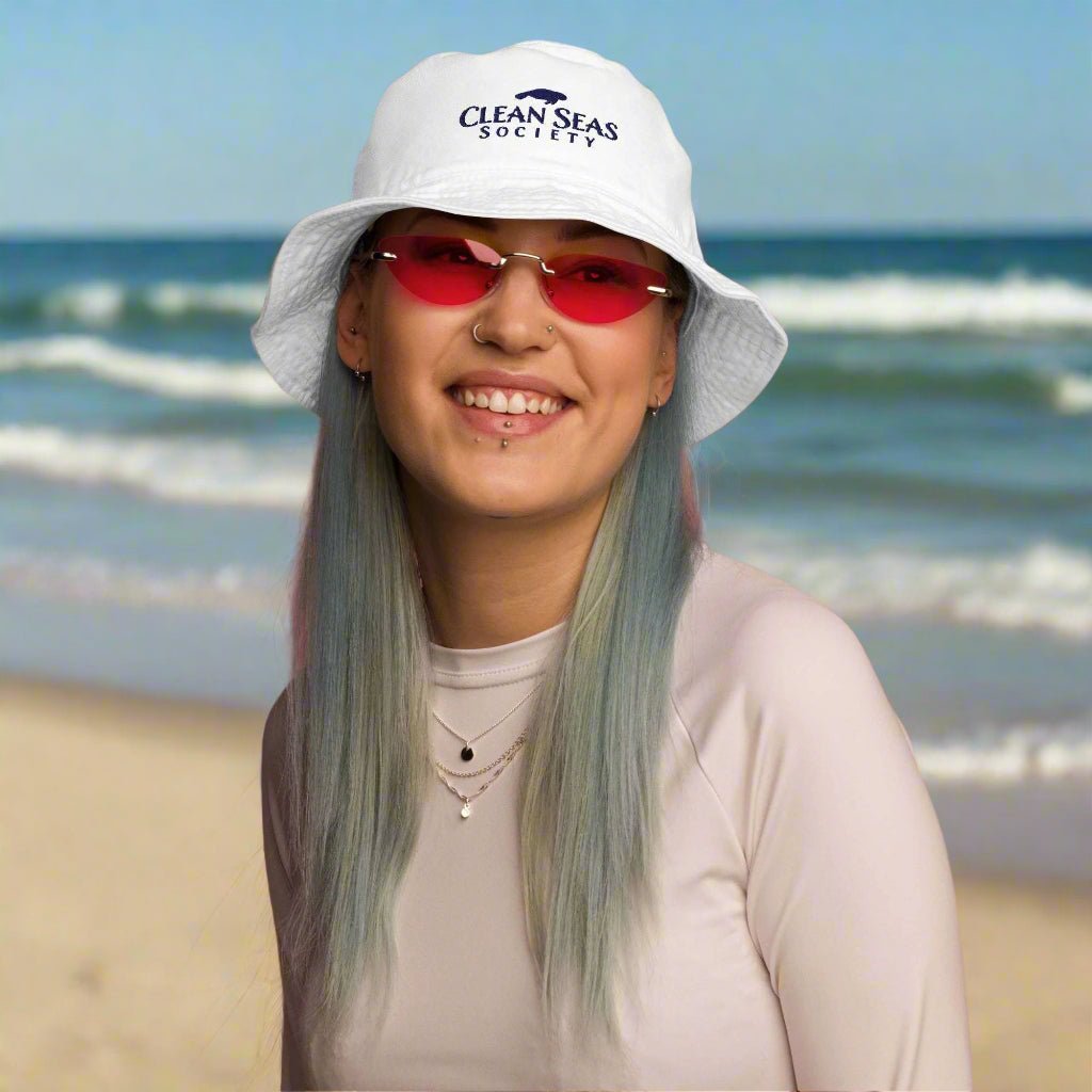 White Organic Bucket Hat with Clean Seas Society logo worn by cute girl doing her part to a beach cleaning party