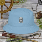 Light blue bucket hat with skull and crossbones design on a wooden background with pirate-themed items.