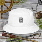 White bucket hat with skull and crossbones design on a wooden background with pirate-themed items.
