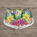 Colorful tropical print shorts worn by a person on a white background