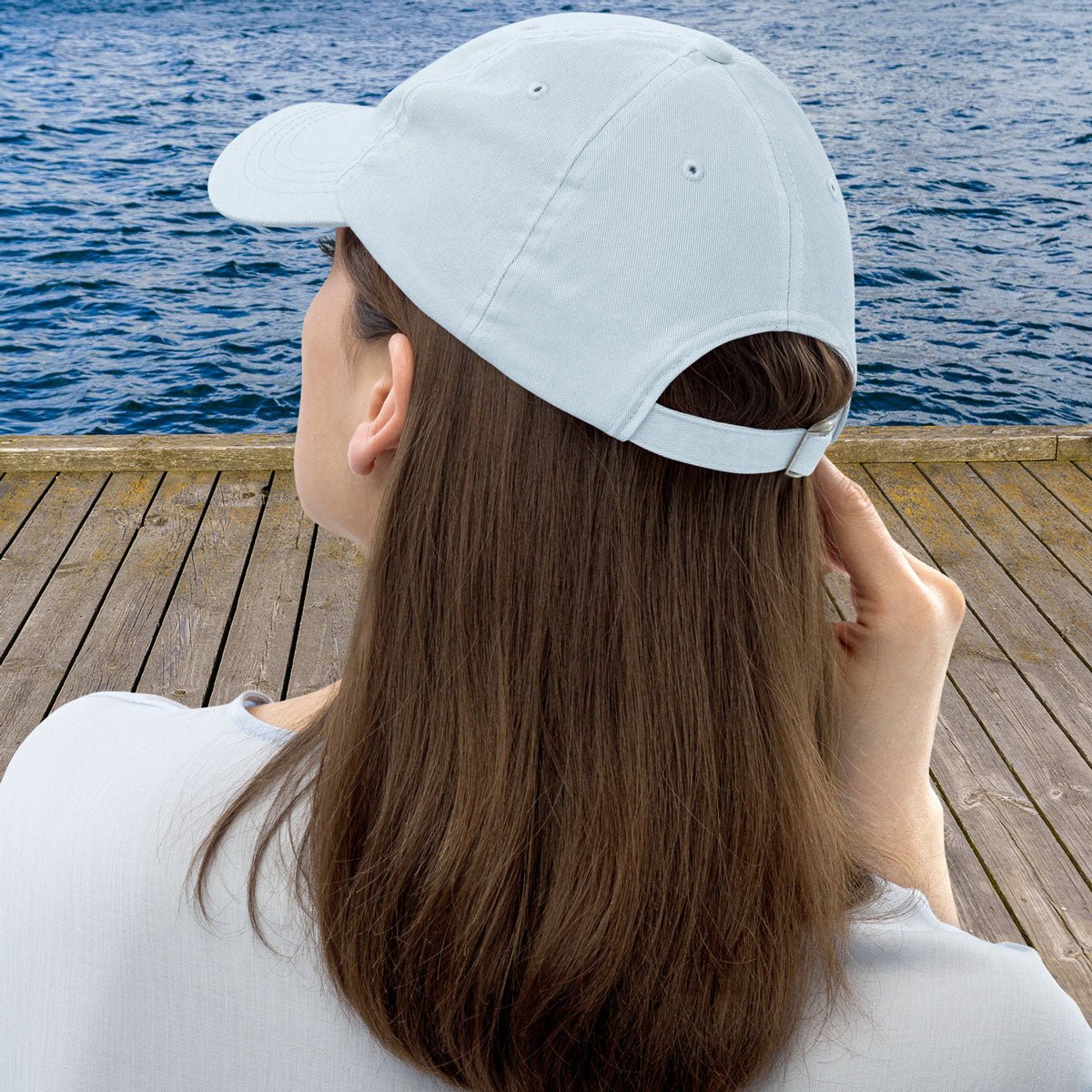 Person wearing a light blue cap by a body of water