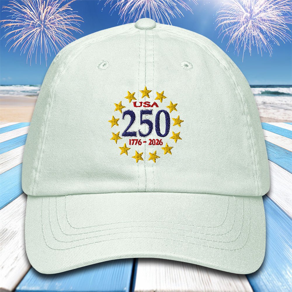 Light green cap with 'USA 250' embroidery on a beach with fireworks background