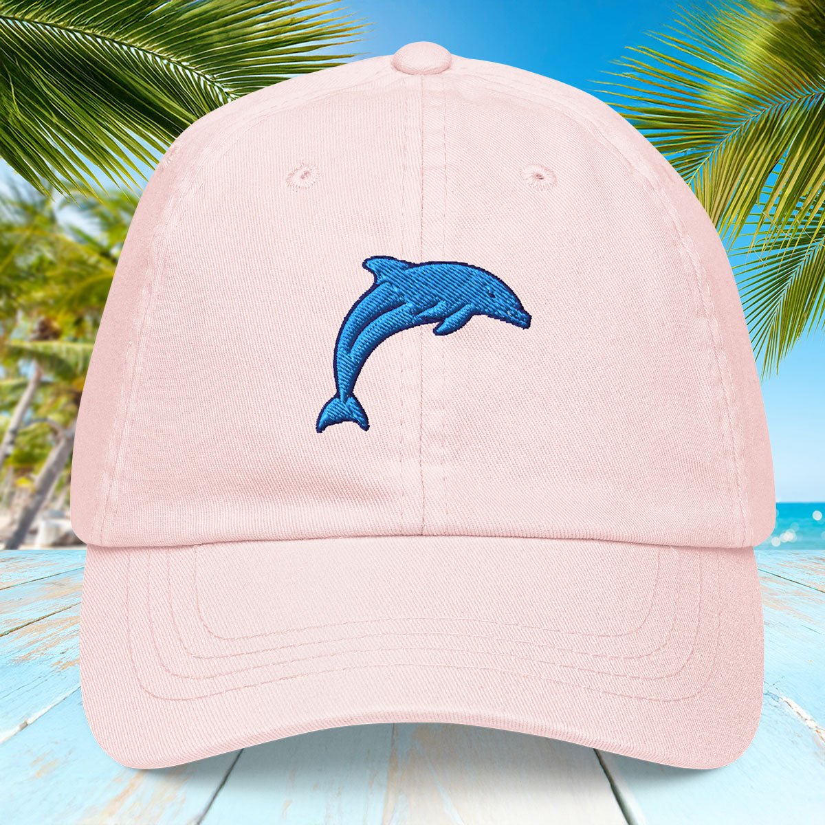 Pink cap with a blue dolphin design on a tropical background