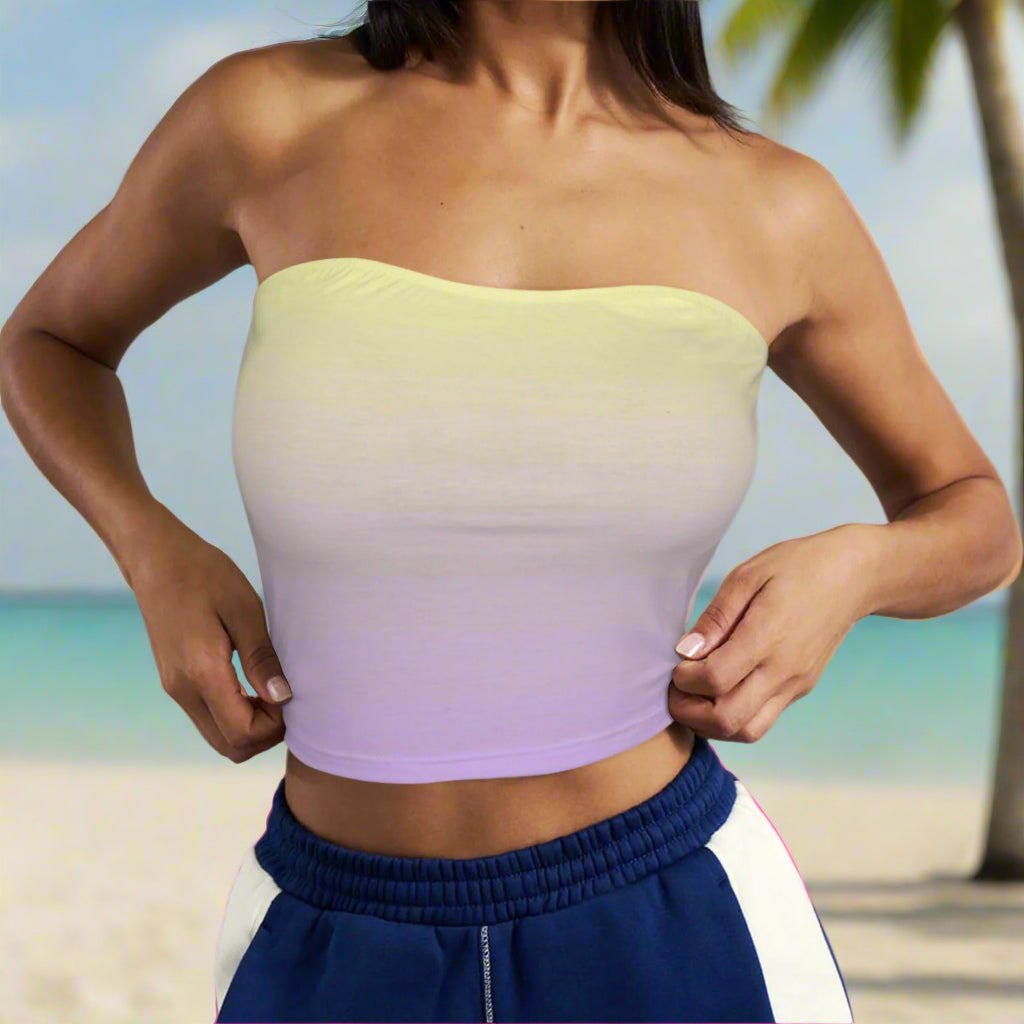 Beachwear model wearing a gradient strapless top with blue pants against an island beach background