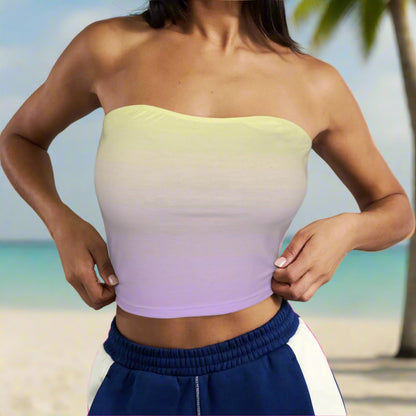 Beachwear model wearing a gradient strapless top with blue pants against an island beach background