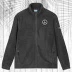 A dark gray fleece zip-up jacket with a stand collar, shown flat against a white wood plank background with a palm leaf pattern overlay. The jacket features a small white circular logo on the left chest and a small white logo on the right sleeve.