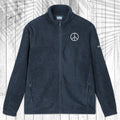A dark Navy fleece zip-up jacket with a stand collar, shown flat against a white wood plank background with a palm leaf pattern overlay. The jacket features a small white circular logo on the left chest and a small white logo on the right sleeve.
