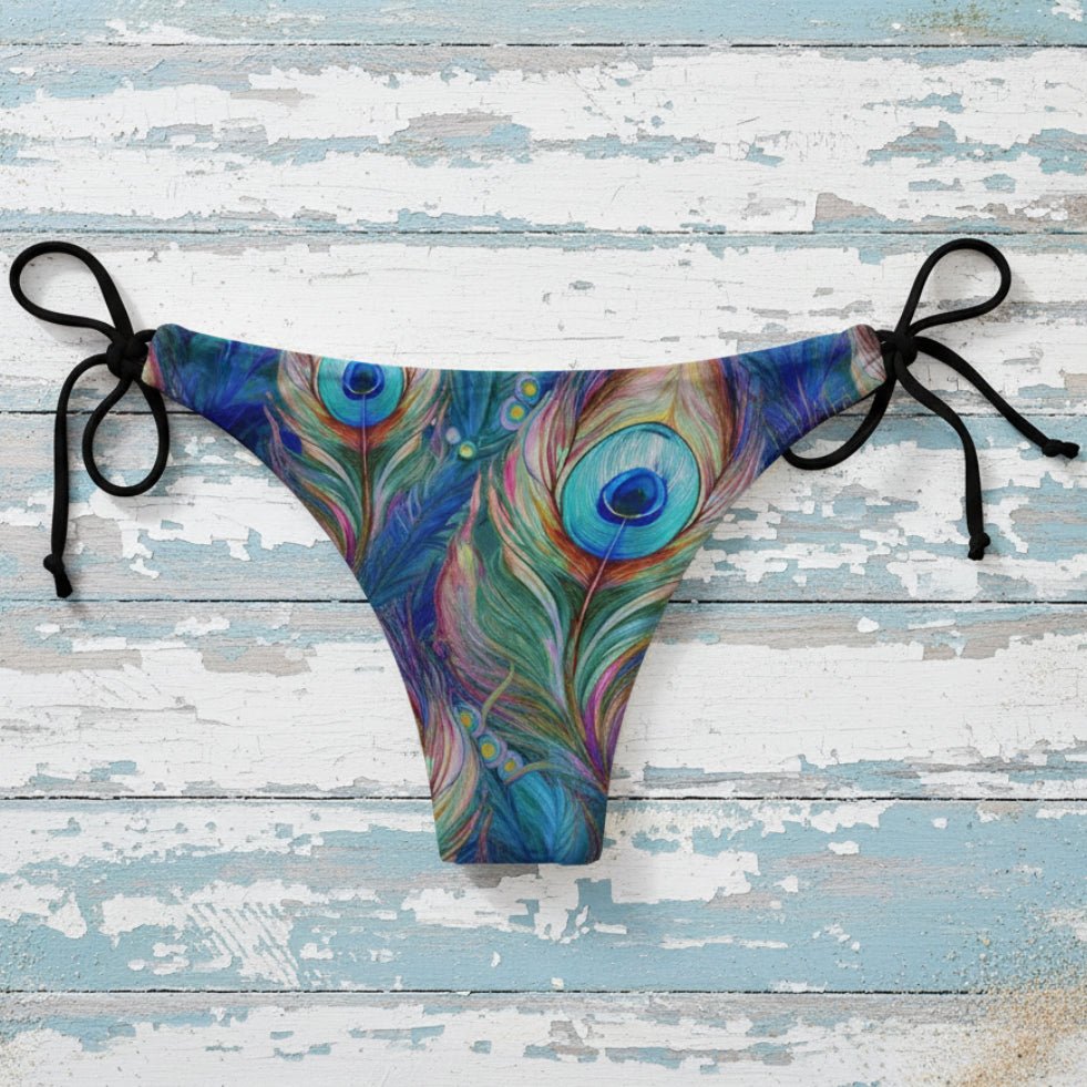 Colorful peacock feather-patterned bikini bottom on a beach.