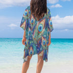 Person wearing a colorful peacock feather patterned cover-up on a beach.