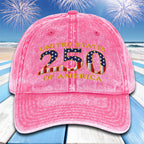 Pink cap with 'United States 250 of America' text and American flag design on a beach with fireworks background.