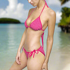 Bikini Model wearing a Pink on Pink Dolphin string bikini set standing in sand on a beautiful beach.
