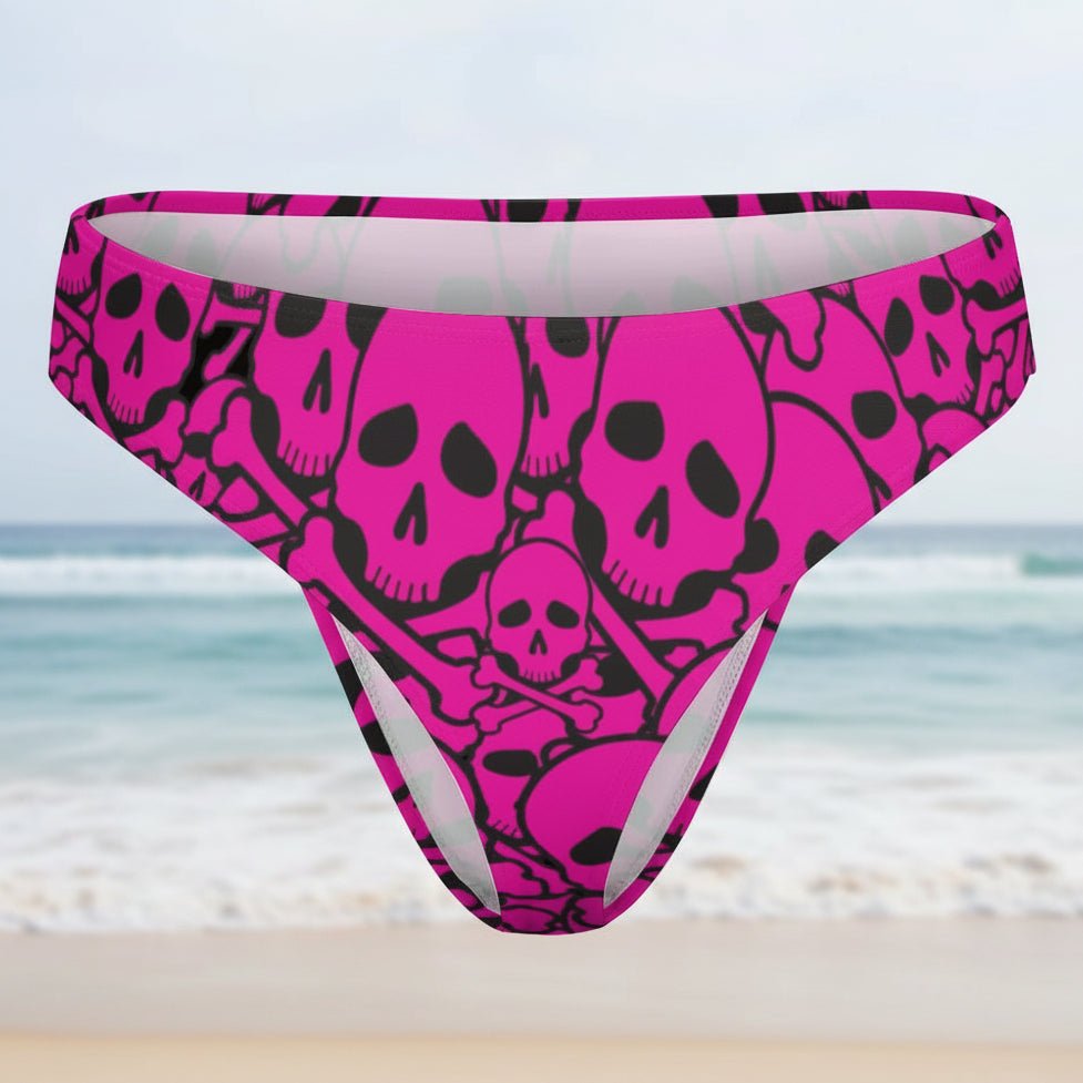 Pink bikini bottom with black skull pattern on a faded beach background