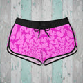 Pink shark pattern shorts with black drawstring on a rustic wood background