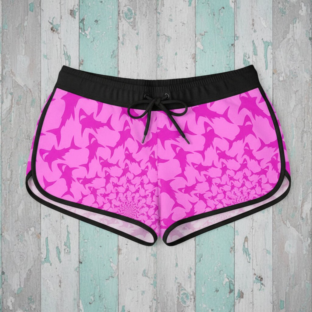 Pink shark pattern shorts with black drawstring on a rustic wood background