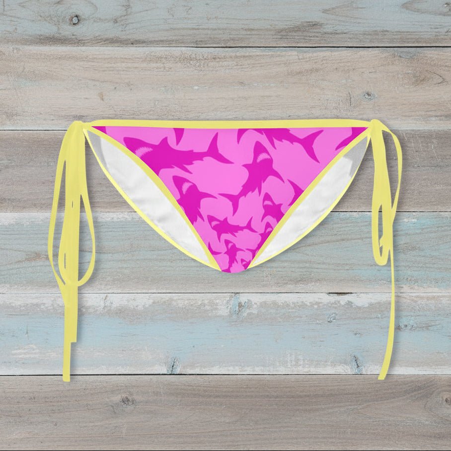 Pink Shark pattern bikini bottom with yellow straps on a rustic wood background