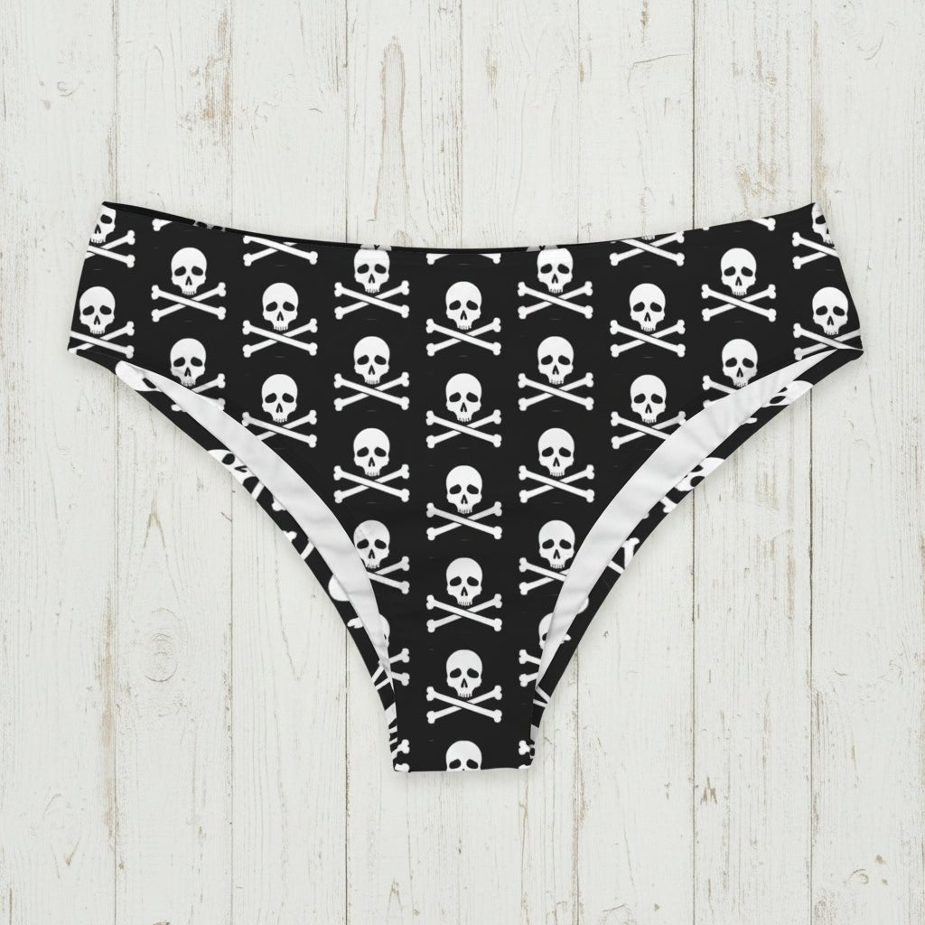 Black bikini bottoms with white skull and crossbones pattern on a nautical wood background