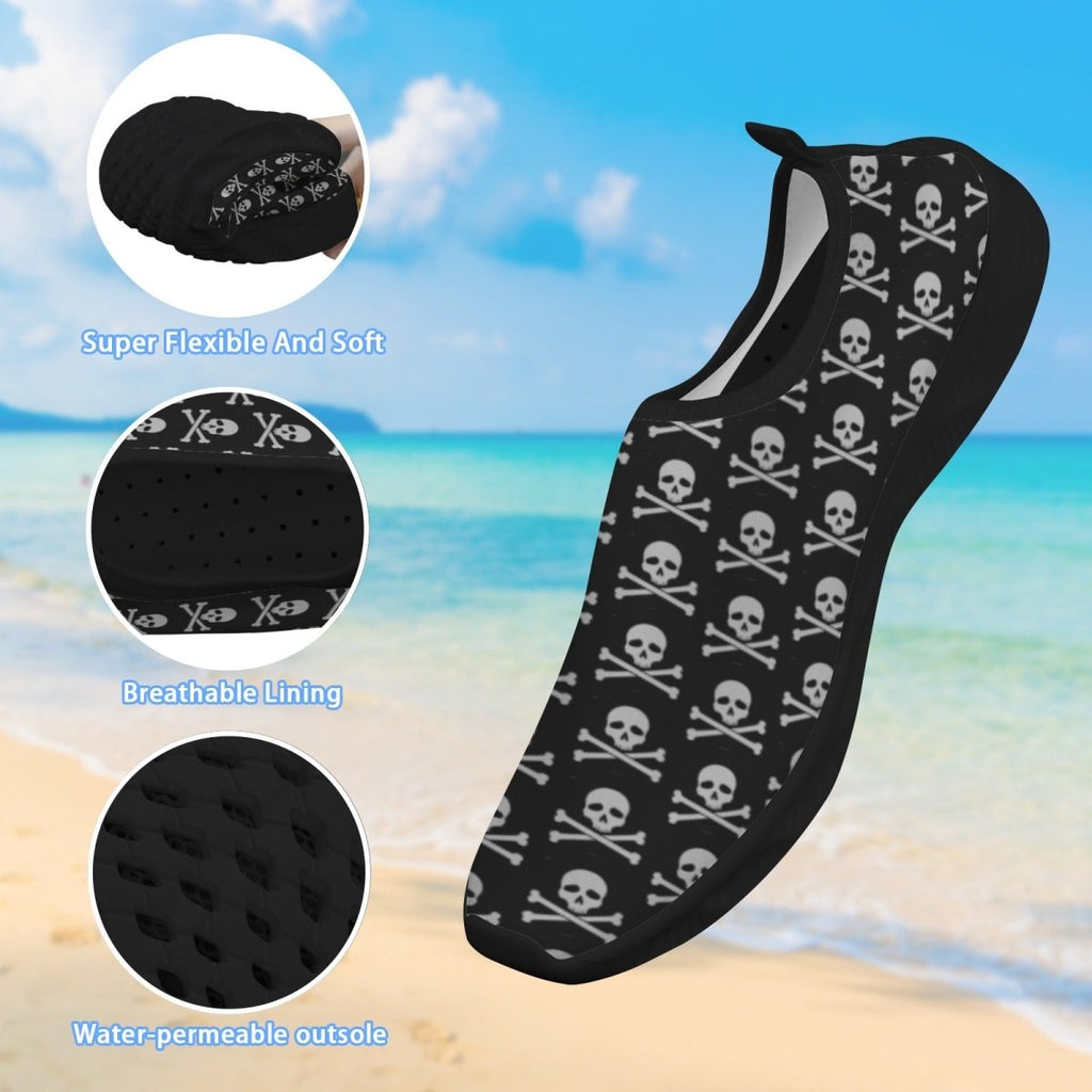 Black slip-on water shoe with a white skull and crossbones pattern, shown over a beach background with three circular detail insets highlighting flexibility, breathable lining, and water-permeable outsole.