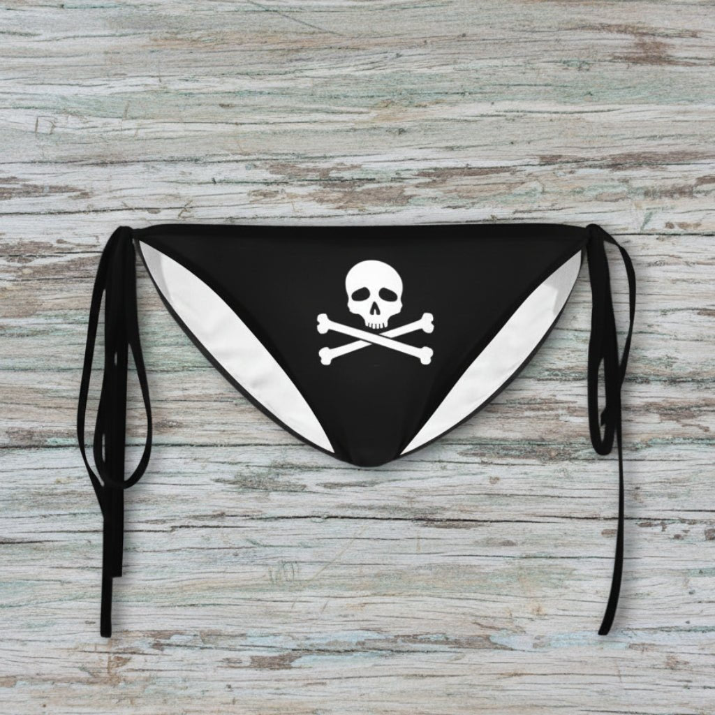 Black bikini bottom with skull and crossbones design on a rustic wood background