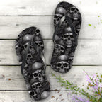 Flip-flops with pirate skull design on a wooden surface with flowers.