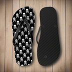 Flip-flop with skull and crossbones pattern and black insole on a nautical wood background