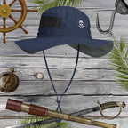 Navy blue sun hat with skull embroidery on a wooden background with pirate-themed items.