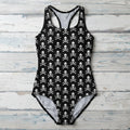 black one-piece swimsuit with a repeating white skull and crossbones pattern against rustic wood background