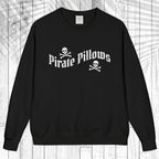 A black crewneck sweatshirt with a white graphic reading 'Pirate Pillows' and skull-and-crossbones icons, displayed flat against a white wood plank background.
