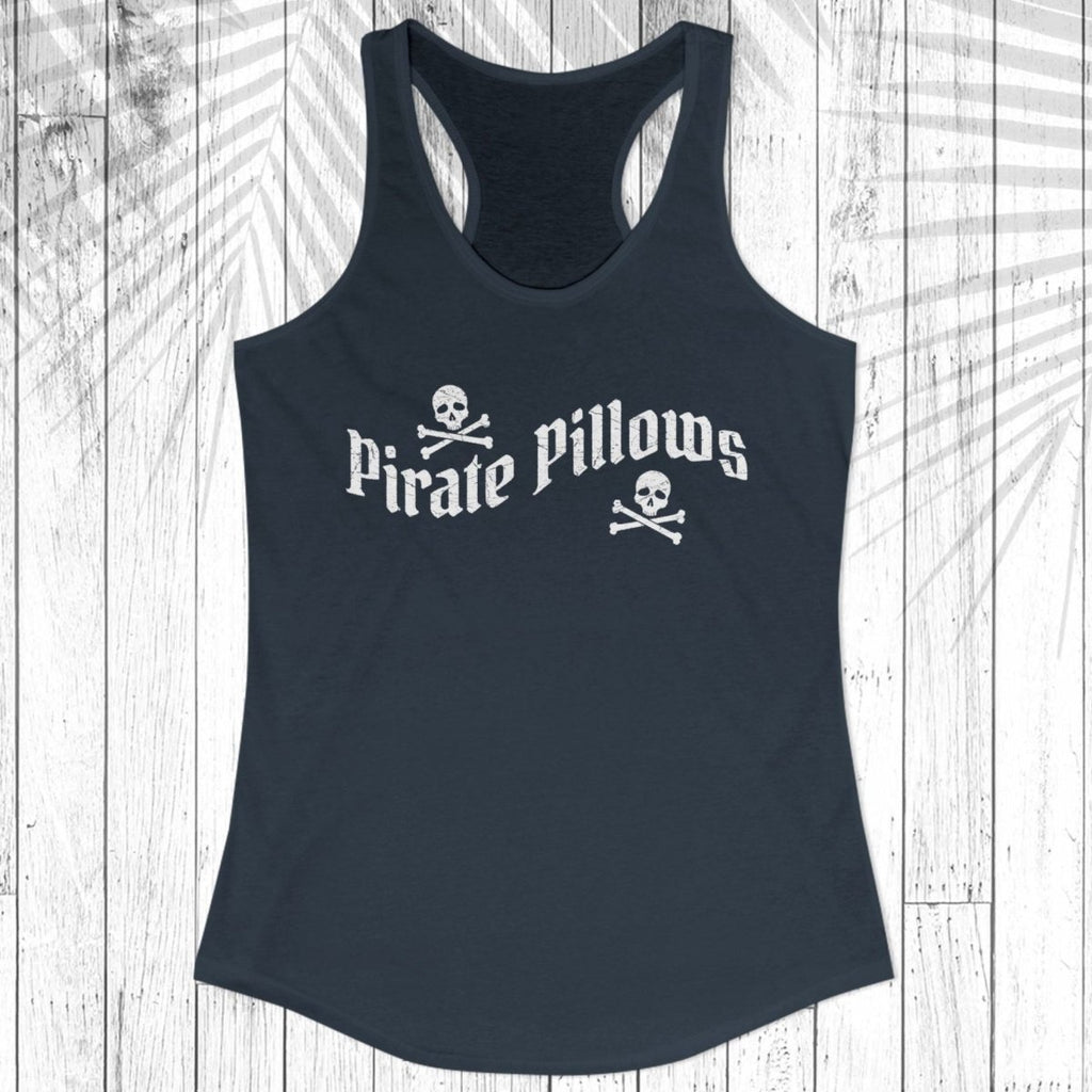 A black racerback tank top with 'Pirate Pillows' and skull-and-crossbones graphics on the front, displayed flat against a white wood plank background.