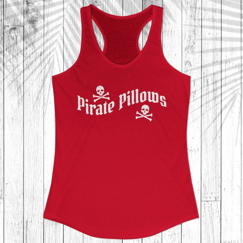 A red racerback tank top with 'Pirate Pillows' printed in white across the chest, displayed on a white wood plank background with a palm leaf overlay.