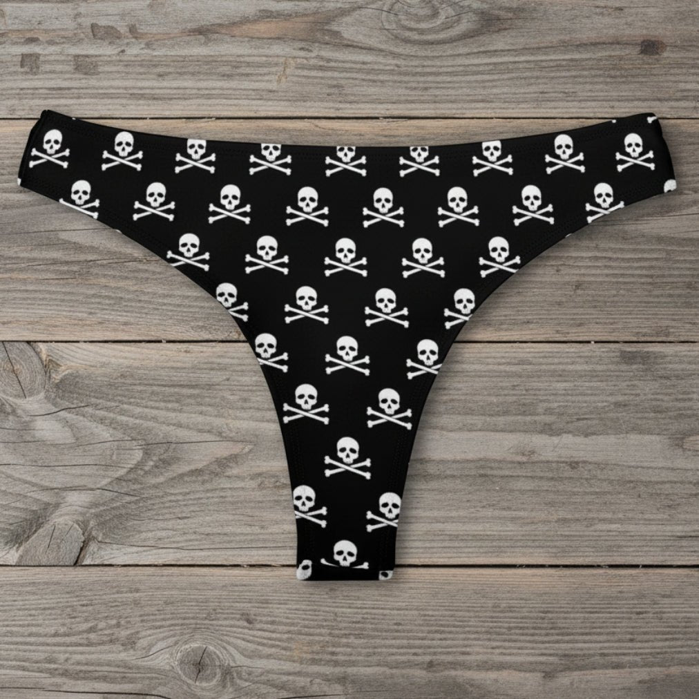 Black thong with white skull and crossbones pattern on a rustic wood background