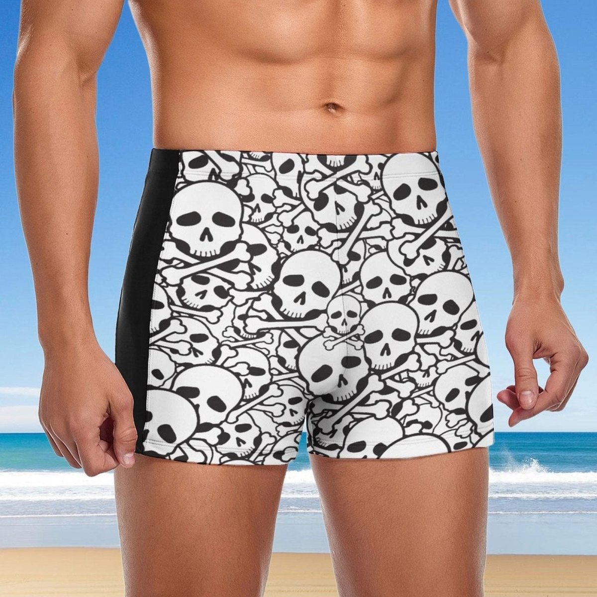 Person wearing black and white skull-patterned swim shorts with a beach background