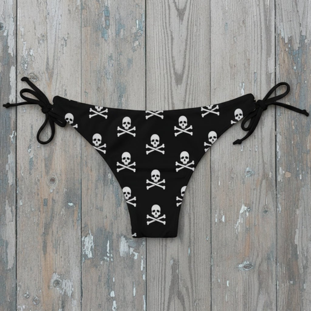 Black bikini bottom with skull and crossbones pattern on rustic wood background
