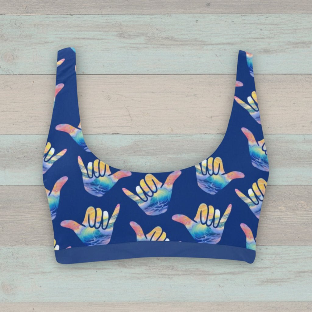 Blue bikini top with colorful hand signs pattern on a rustic wood background