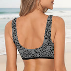 Woman wearing a gray sports bikini top with black skull pattern on a faded beach background