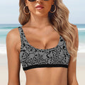 Woman wearing a black and gray pirate patterned sports bra on a faded beach background