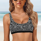 Woman wearing a black and gray pirate patterned sports bra on a faded beach background
