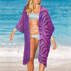 Woman on a beach wearing a purple tiger-striped Beach Cover Up and white bikini.