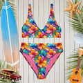 Colorful floral surf bikini set on a wooden background with beach accessories.