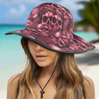 Pink skull-patterned bucket hat worn by a model on a caribbean beach background