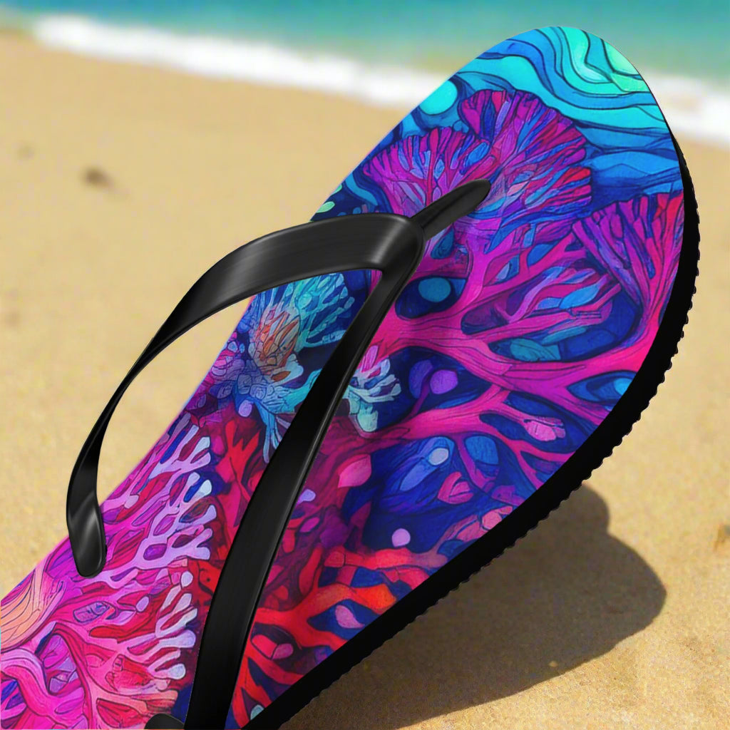 Colorful coral-patterned sandal with a black strap on a sunny beach background