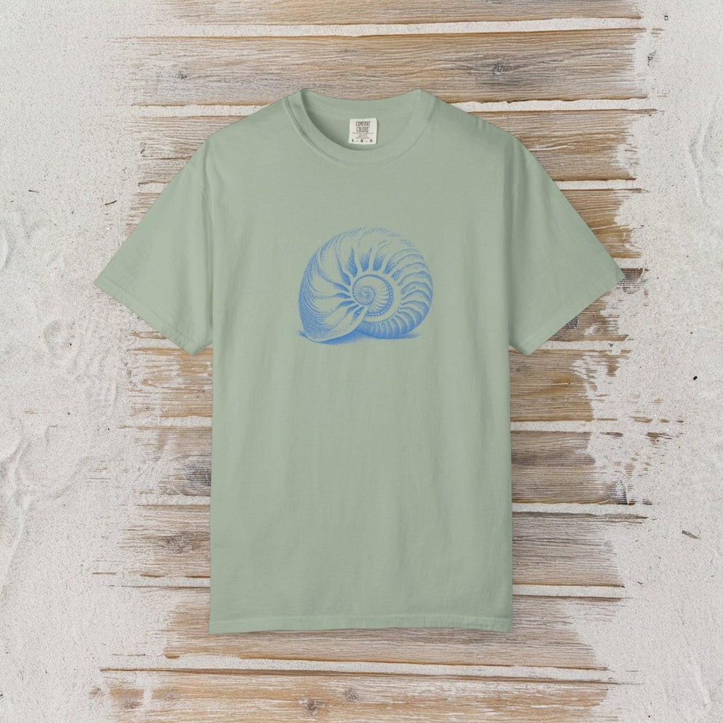 A sage green short-sleeve t-shirt with a blue spiral shell graphic on the chest, displayed flat on a rustic wooden plank background.