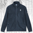A dark Navy fleece zip-up jacket with a stand collar, shown flat against a white wood plank background with a palm leaf pattern overlay. The jacket features a small white circular logo on the left chest and a small white logo on the right sleeve.