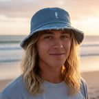 dude wearing a light blue denim bucket hat with a small white seahorse embroidery on the front